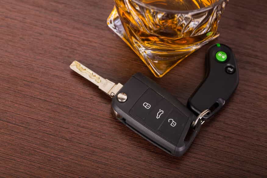 Keys and Glass of Alcohol on a Wood Table 